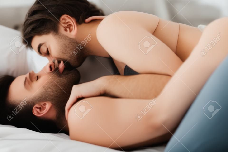 Junges Paar leidenschaftlich küssen beim Liegen im Bett