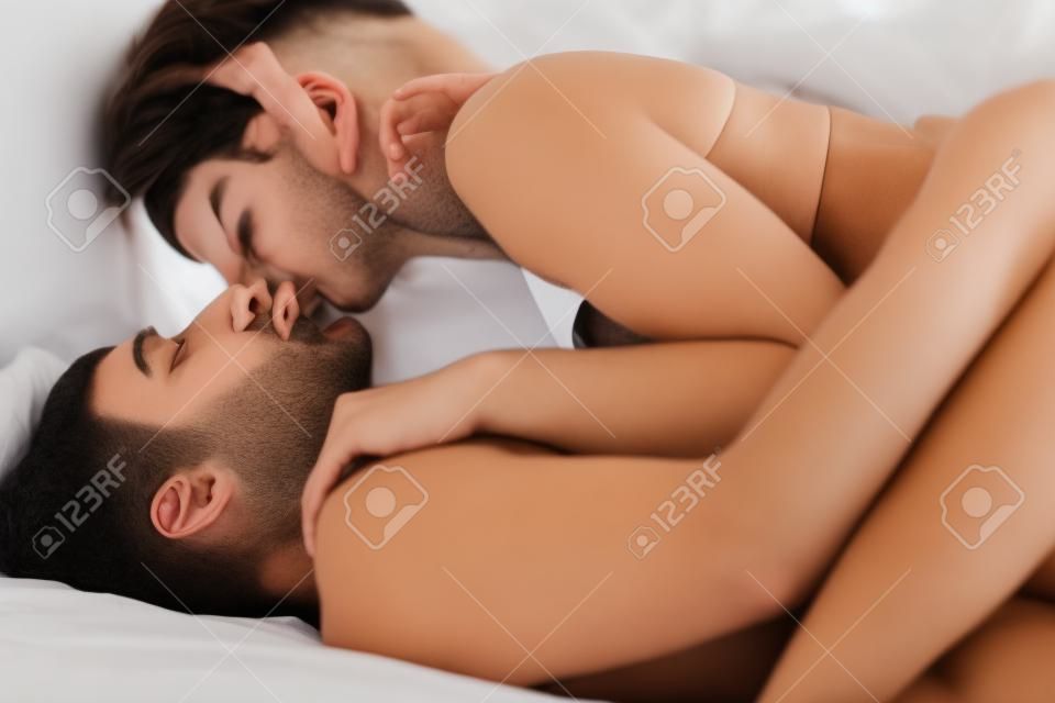 Молодая пара страстно целоваться, лежа в постели