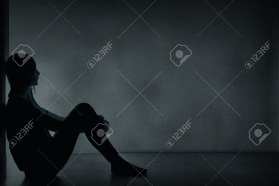 Nastolatka z depresji siedzi sam w ciemnym pokoju