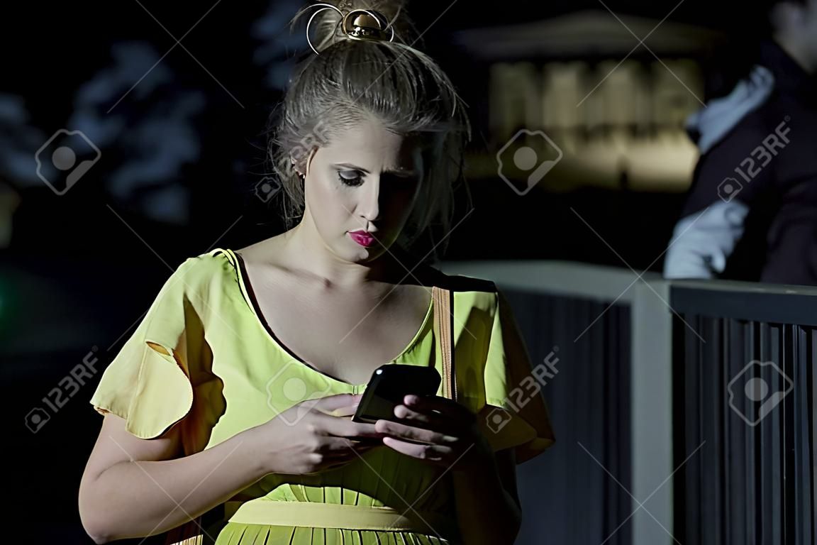 Donna con il telefono cellulare che cammina da solo di notte