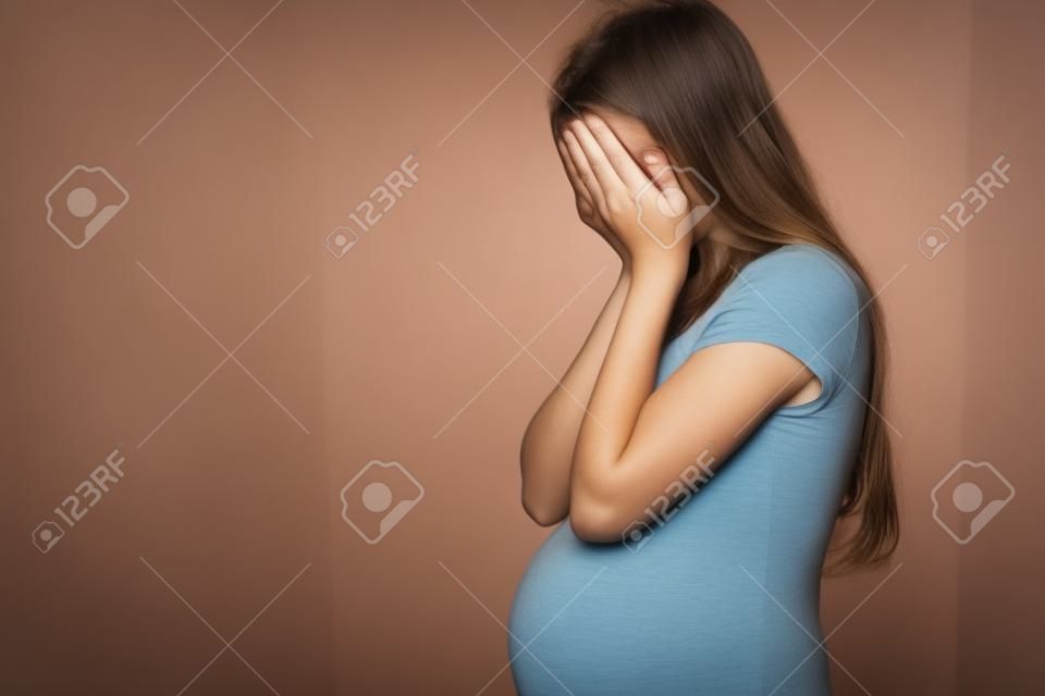 Yüzünü elinde saklayan hamile bir genç kızın görüntüsü