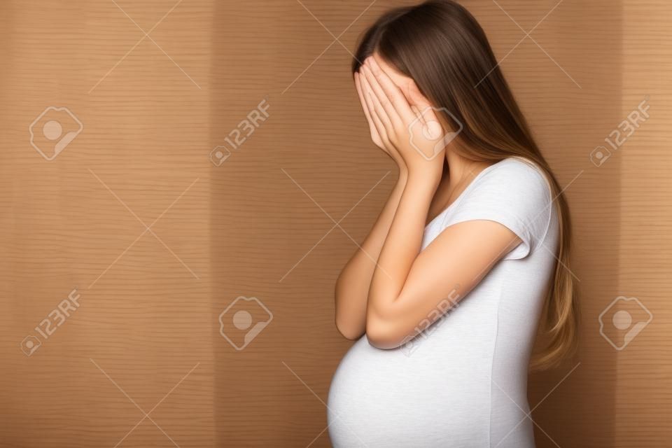 一個懷孕的少女形象躲在她的臉在她的手中