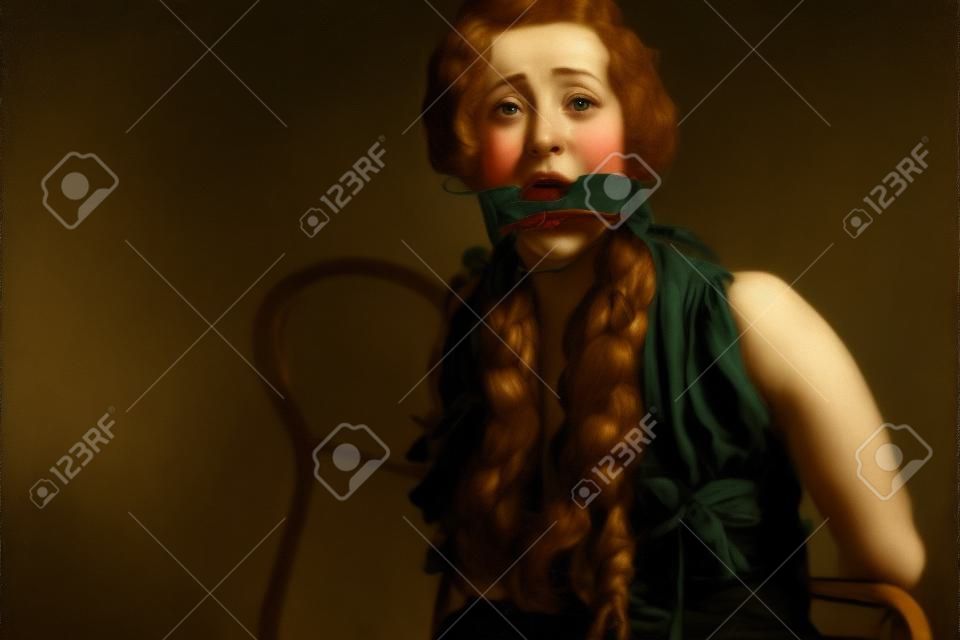 Erschrockene junge Frau an einen Stuhl gefesselt und mit einem Knebel in den Mund