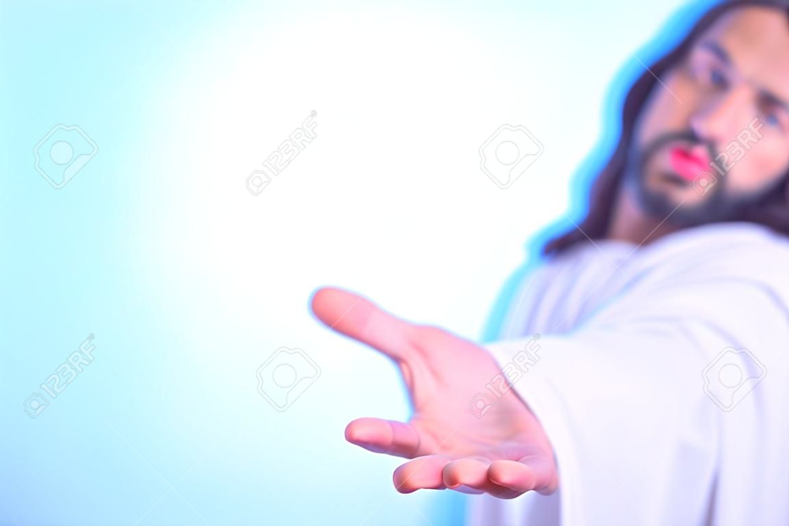 밝은 배경에 고립 된 손을 밖으로 도달하는 예수의 실루엣