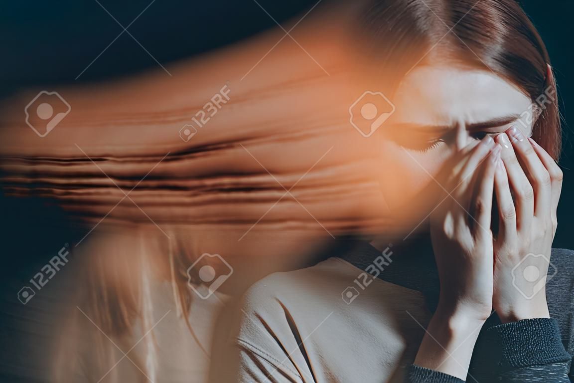Young woman with emotional problems covering her face, crying