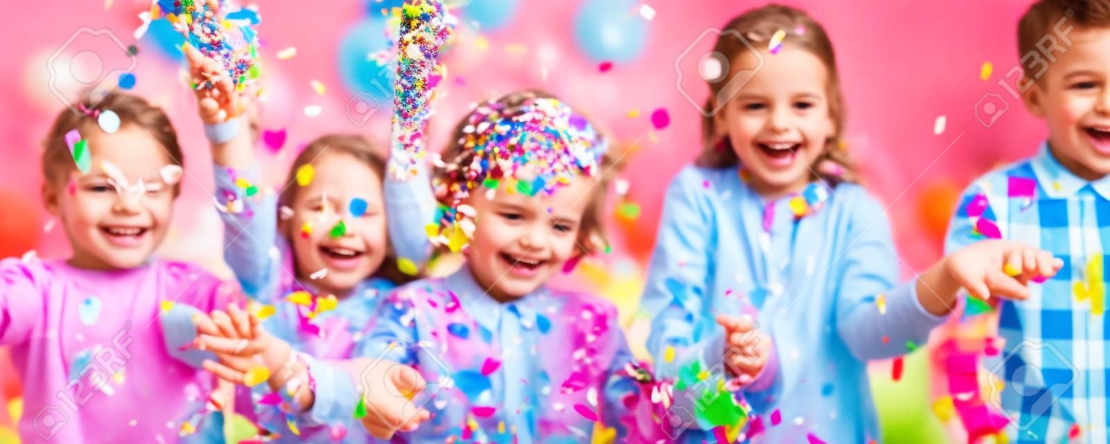 Uśmiechnięci dzieciaki bawić się z confetti przy przyjęciem urodzinowym