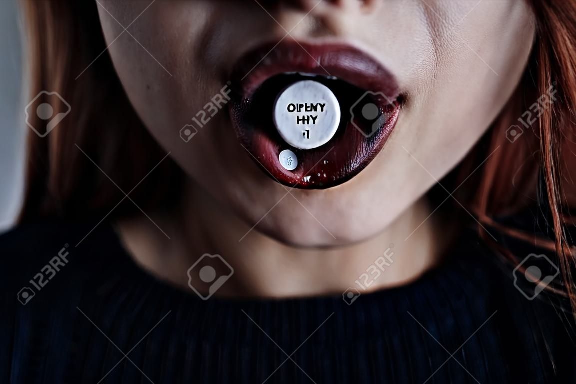 Close-up of girl's mouth with a pill on tongue. Drug addiction concept