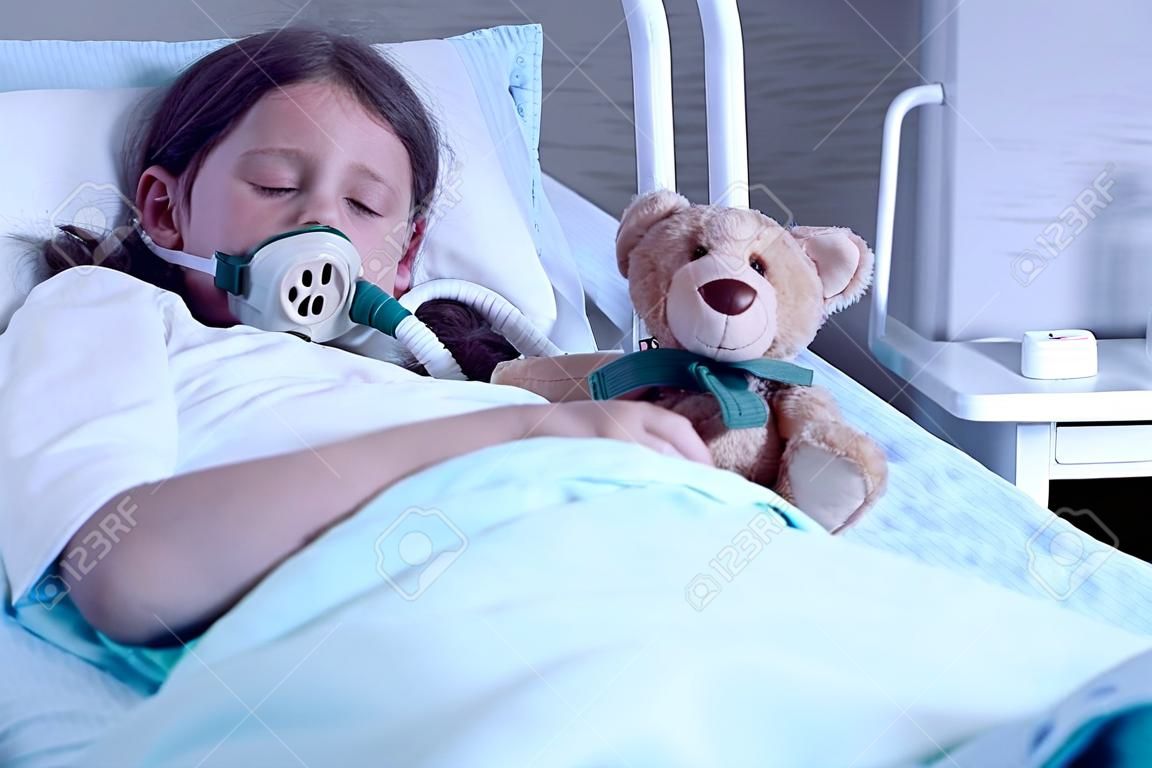 Dziecko z mukowiscydozą leżące w szpitalnym łóżku z maską tlenową i pluszową zabawką