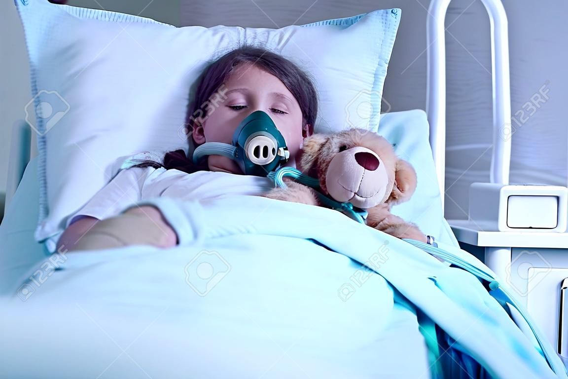 Criança com fibrose cística deitado em uma cama de hospital com máscara de oxigênio e brinquedo de pelúcia