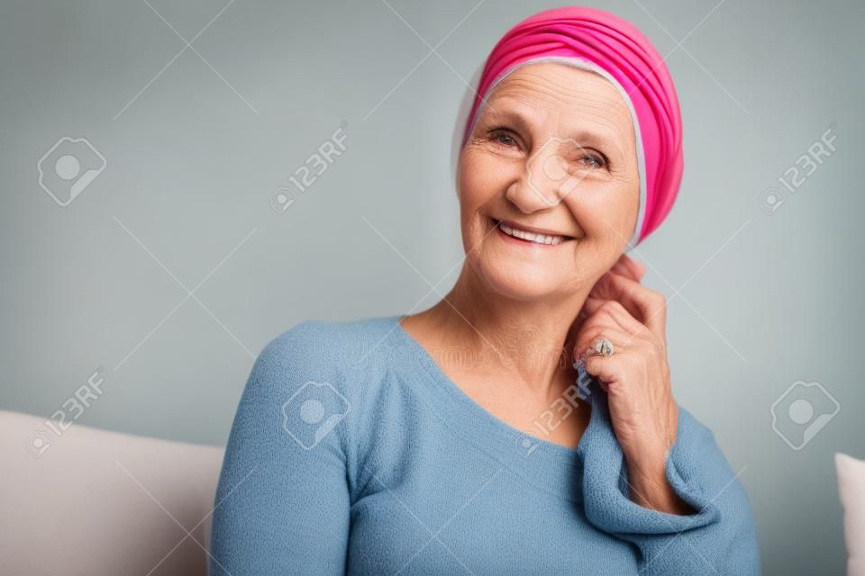 Boldog, idős nő portréja egy fejkendőben a rákos betegek számára, felépülve a betegségből