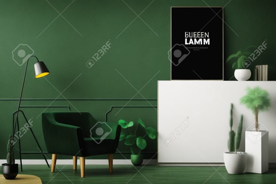 Black lamp next to green armchair in living room interior with plants and mockup of poster