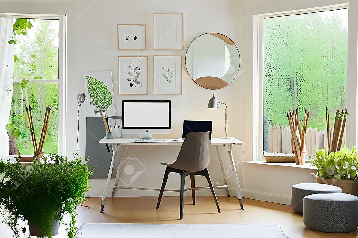 Grey chair at desk with desktop computer in scandi open space interior with windows. Real photo
