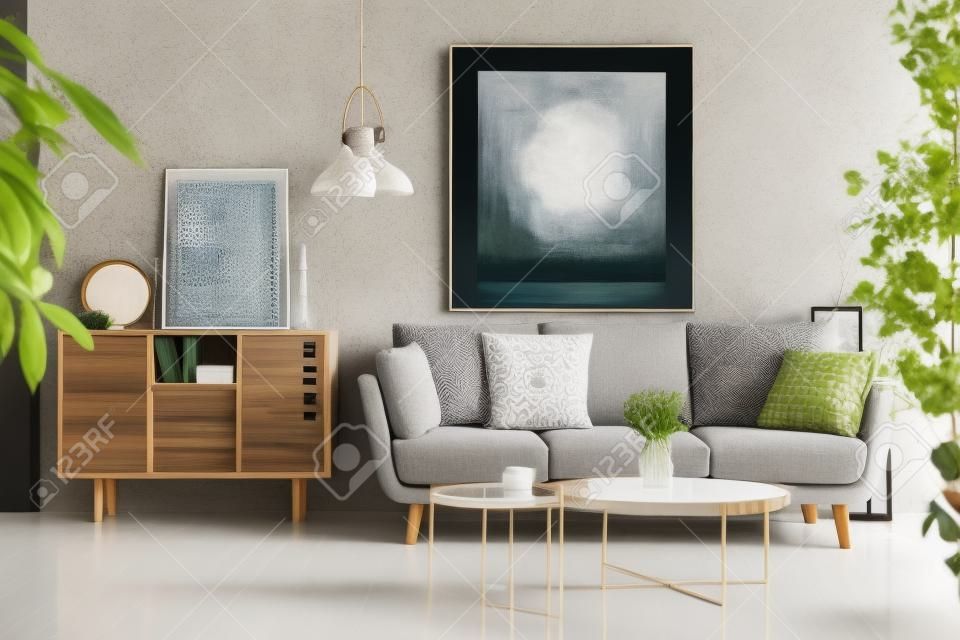 Echtes Foto eines Holzschranks neben einem Sofa in einem modernen Wohnzimmerinnenraum mit einem großen Gemälde