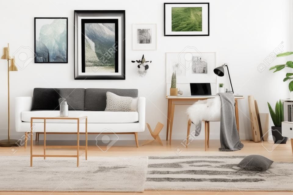 Framed photos gallery on a white wall of a hipster living room interior and workspace with laptop on a wooden desk