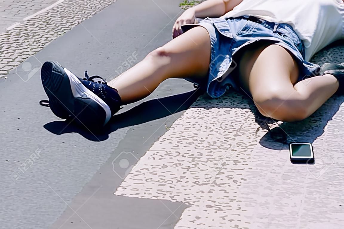 Onbewust meisje liggend op een straat naast haar mobiele telefoon