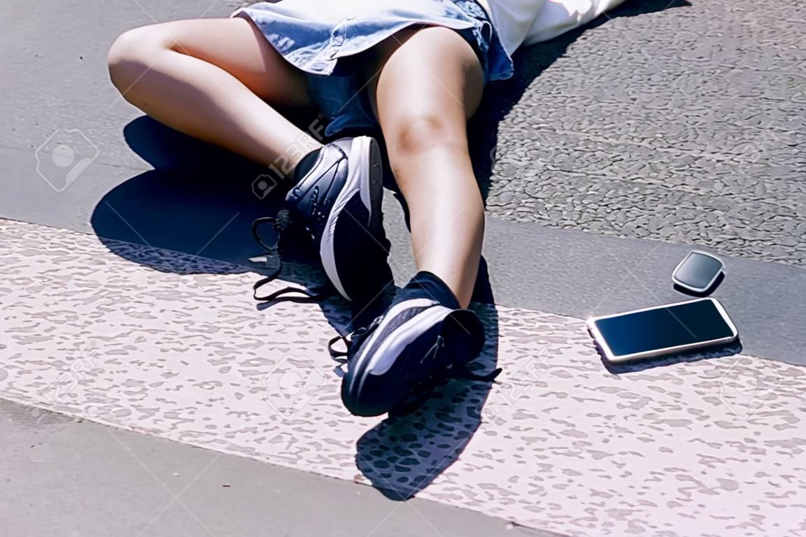 彼女の携帯電話の隣の通りに横たわっている意識不明の女の子