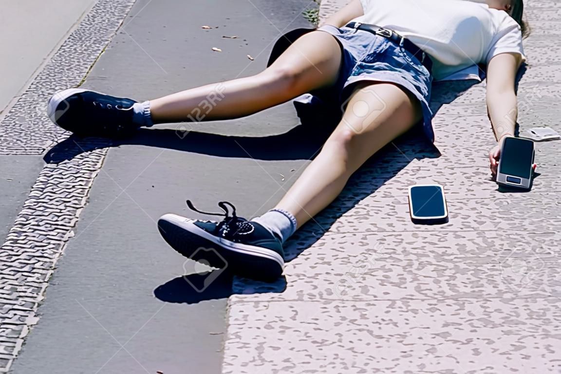 Onbewust meisje liggend op een straat naast haar mobiele telefoon
