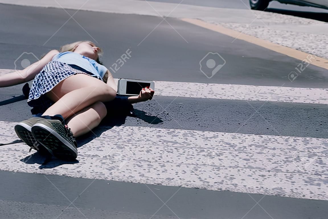 Adolescente con teléfono móvil tirado en la calle después de un terrible accidente automovilístico en el paso de peatones