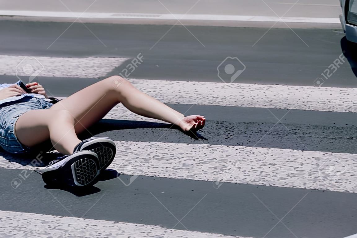 Nastolatka z telefonem komórkowym leżąca na ulicy po strasznym wypadku samochodowym na przejściu dla pieszych