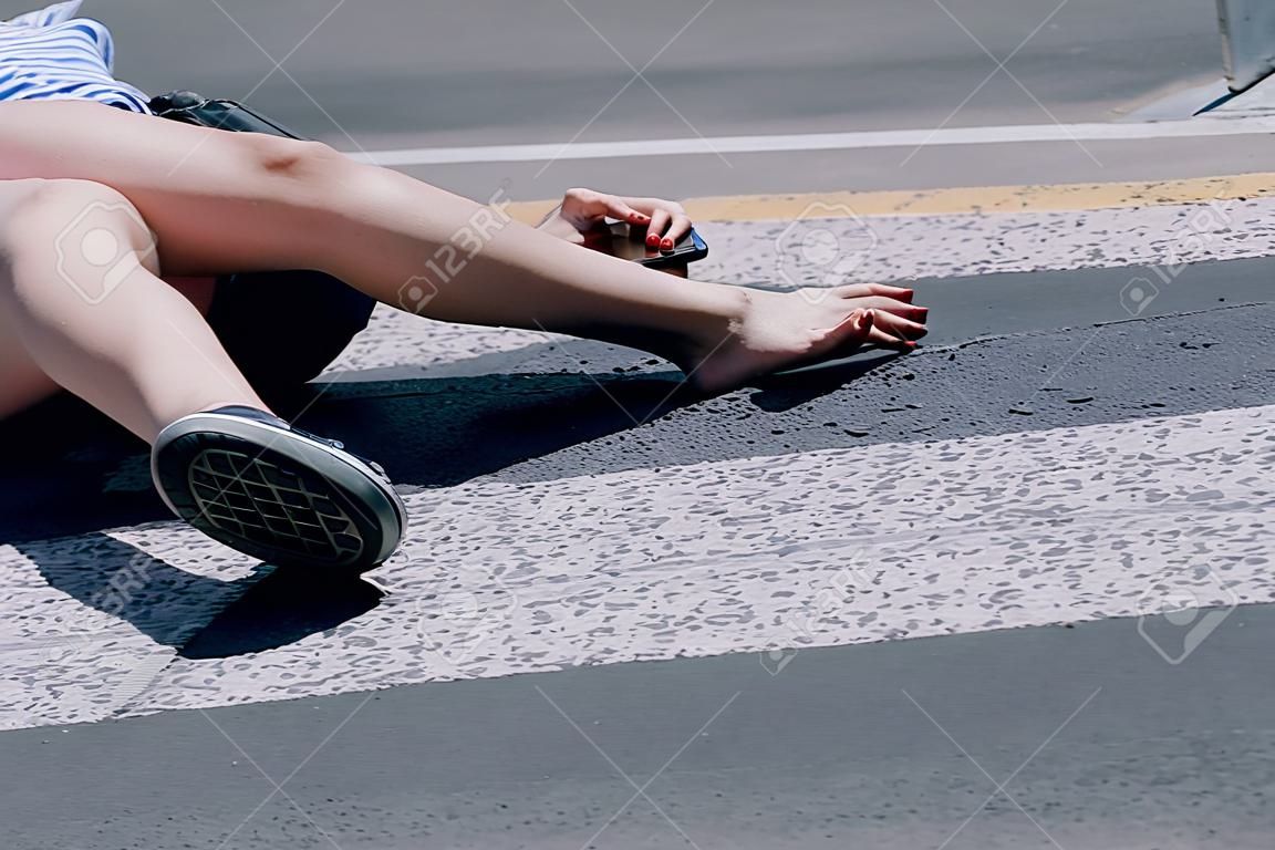 Nastolatka z telefonem komórkowym leżąca na ulicy po strasznym wypadku samochodowym na przejściu dla pieszych