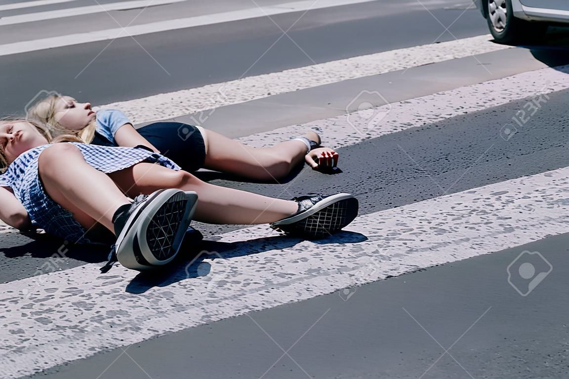 Teenage girl with mobile phone lying on the street after terrible car crash on pedestrian crossing