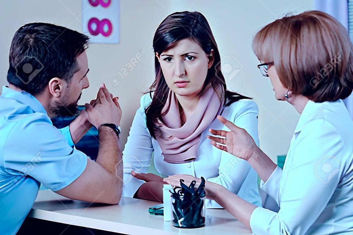 Worried couple consulting with female doctor on medical healthcare therapy