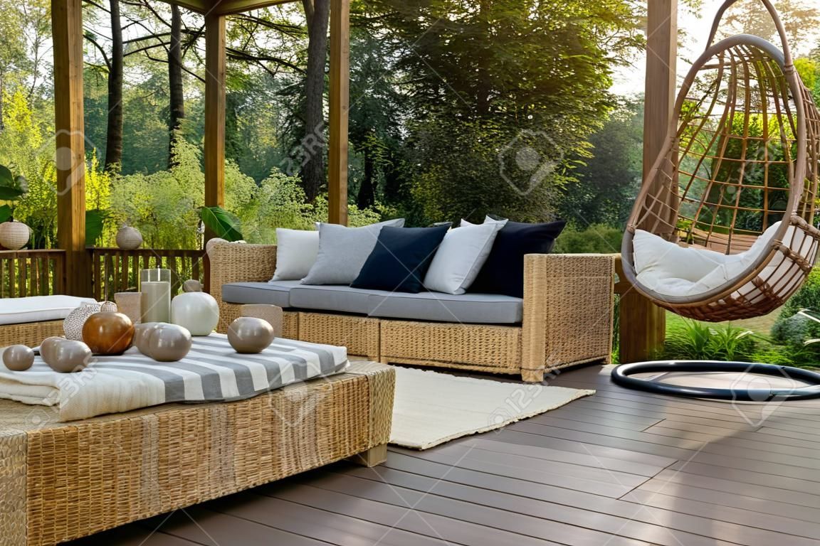 Cozy porch with wooden floor, rattan furniture and hanging chair