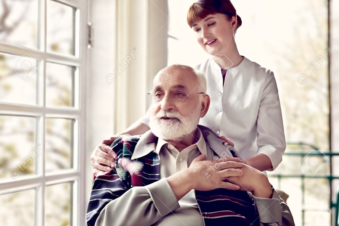 Older man and his helpful young nurse supporting him