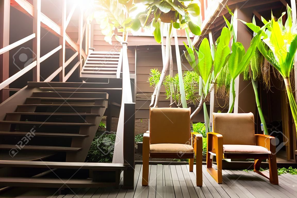 Escalier en bois avec fauteuil et plante en terrasse.