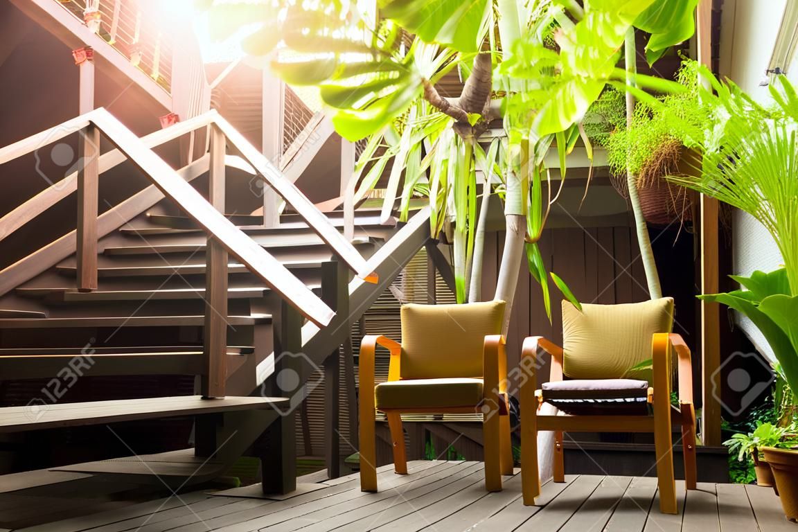 Escalier en bois avec fauteuil et plante en terrasse.