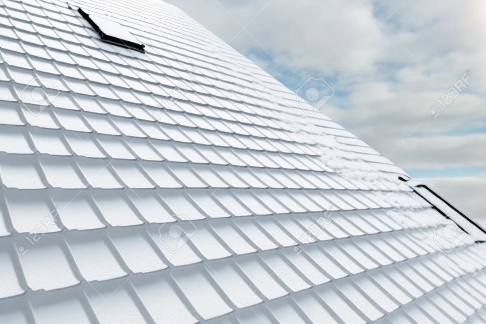 철제 포진으로 덮인 집 옥상에서 겨울철 안전을 위한 눈 보호대. 건물의 타일 덮개