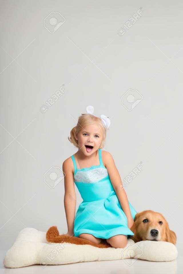 schattig klein blond meisje zitten op een grote zachte hond speelgoed op witte achtergrond