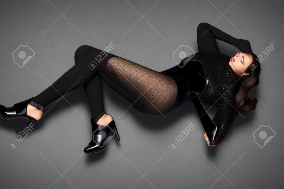 Hübsches Brunettemädchen mit langen Beinen in den schwarzen Schuhen