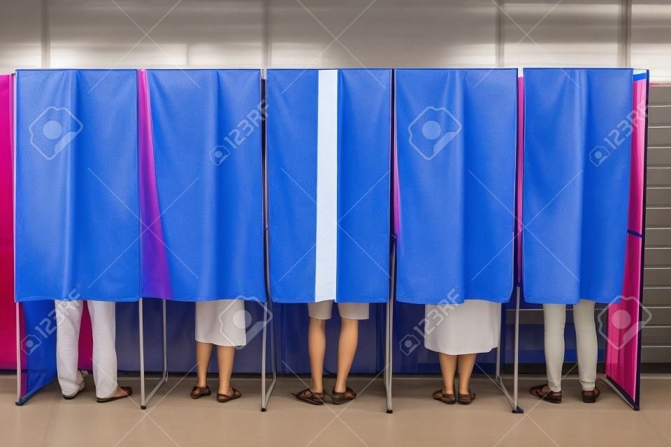 Farbe Bild von einigen Menschen in einigen Wahlkabinen in einem Wahllokal wählen.