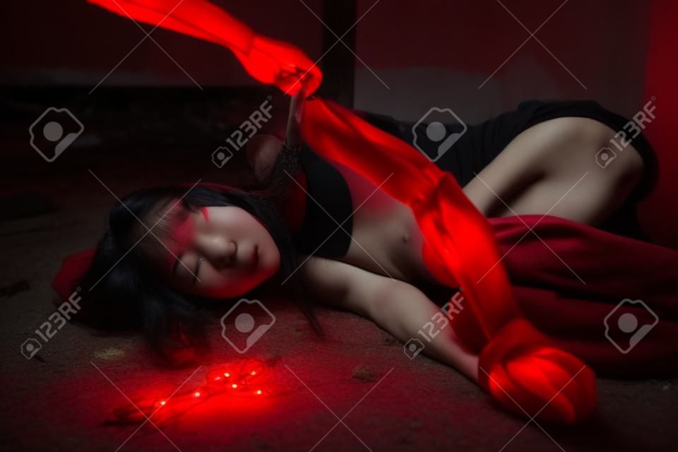 Bad guy man hand take off vitim Asian woman clothes in abandoned house. Scared female tied hands and leds by red rope. Raping and Criminal theme. Social problem concept