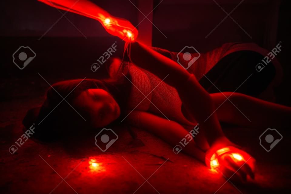 Bad guy man hand take off vitim Asian woman clothes in abandoned house. Scared female tied hands and leds by red rope. Raping and Criminal theme. Social problem concept