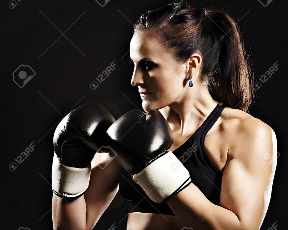 Beautiful muscular fitness woman wearing boxing gloves 