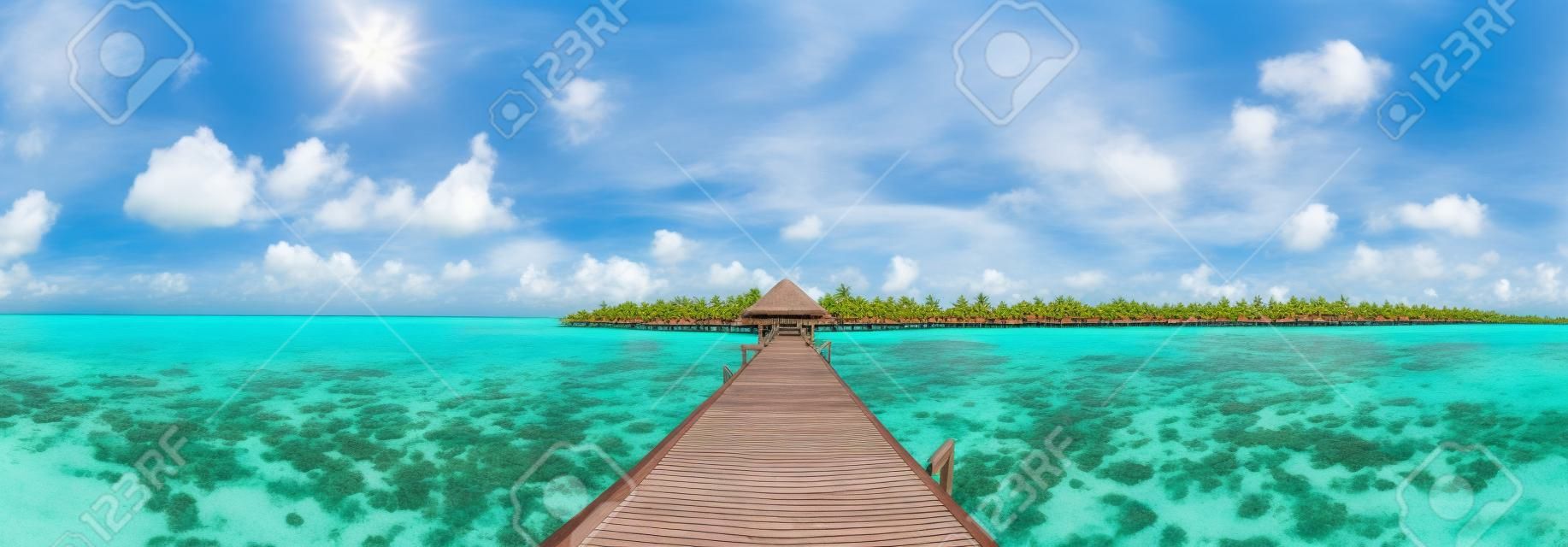 Panorama des villas sur l'eau (bungalows) et pont en bois à la plage tropicale aux Maldives au jour d'été