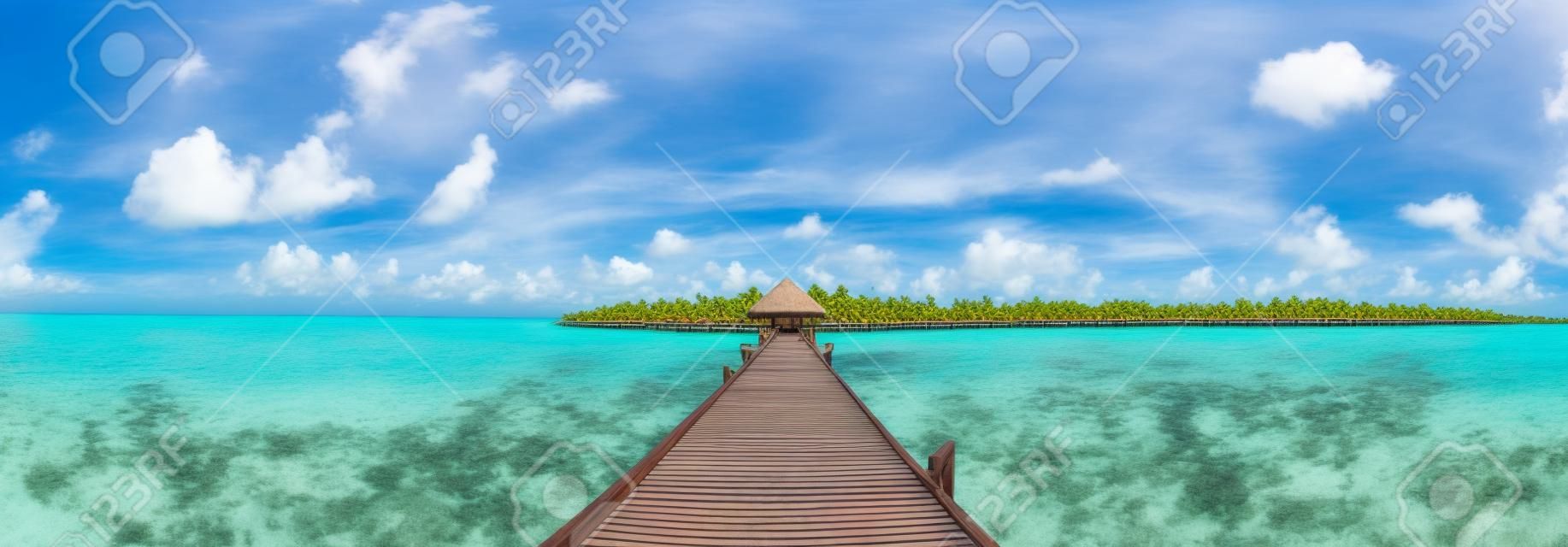 Panorama der Wasservillen (Bungalows) und der Holzbrücke am tropischen Strand auf den Malediven am Sommertag
