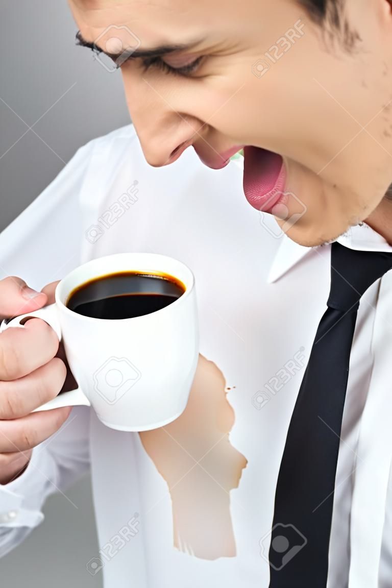 Человек разлив кофе на белой рубашке, попивая