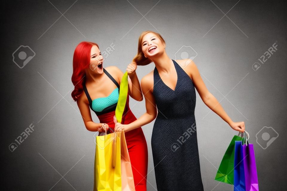 Ben ilk oldu! Mücadele alışveriş torbaları ile iki öfkeli kadın, renkli arka plan üzerinde izole ederken