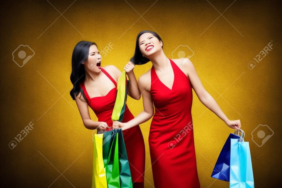 Ben ilk oldu! Mücadele alışveriş torbaları ile iki öfkeli kadın, renkli arka plan üzerinde izole ederken