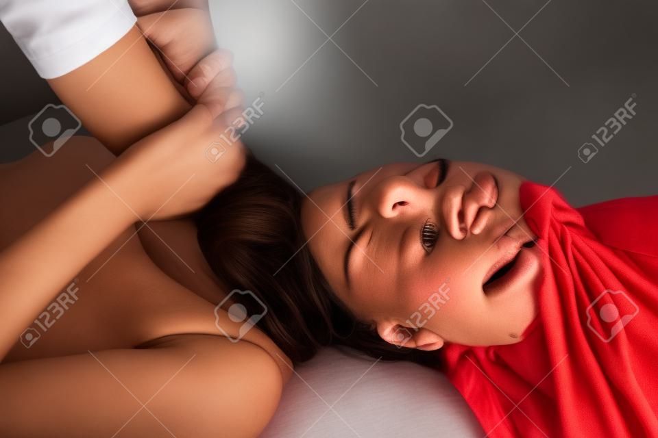 Nahaufnahme des erschrockenen Frau erwürgt. Kampf mit ihrem Freund in einem Bett