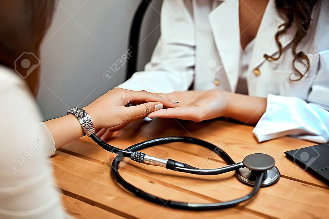 Hand des Arztes, der ihre Patientin beruhigt.