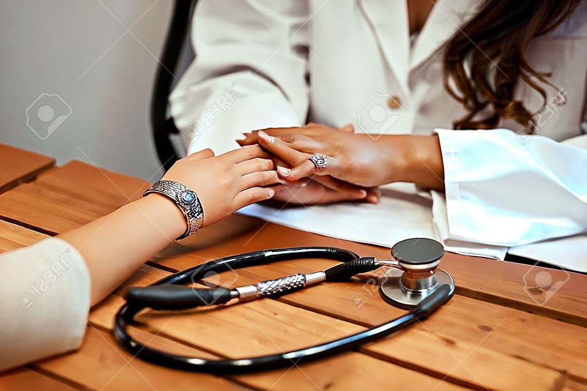 Hand of doctor reassuring her female patient.