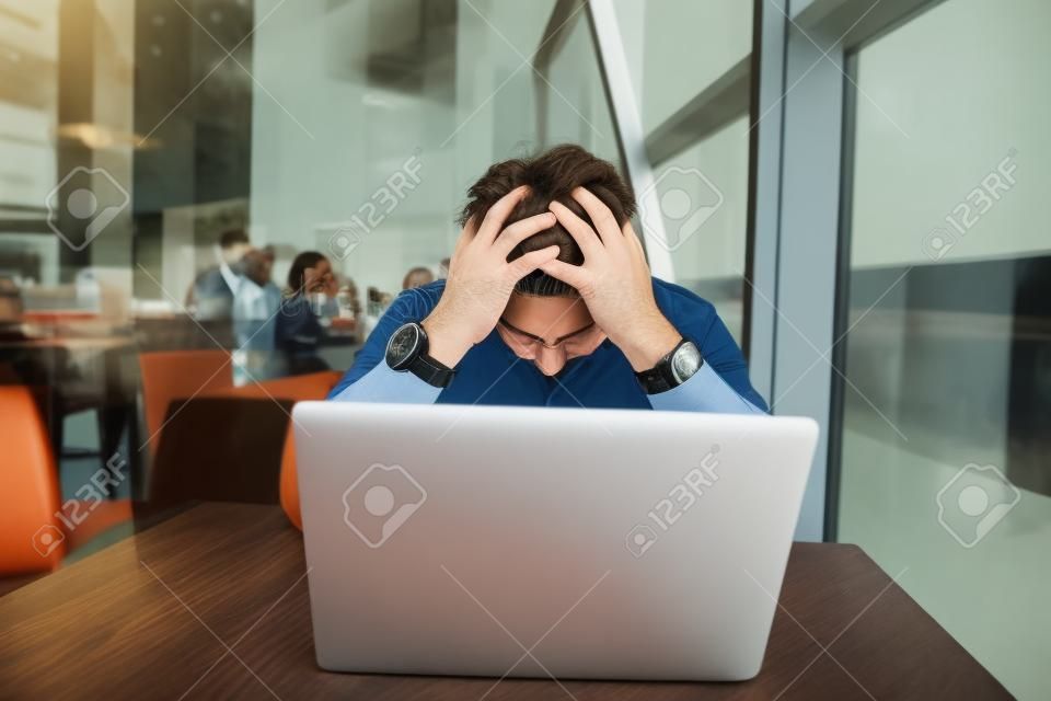 Portrait d'un homme frustré travaillant sur un ordinateur portable dans un café. Un homme d'affaires triste a baissé la tête après l'échec. L'homme d'affaires a échoué.