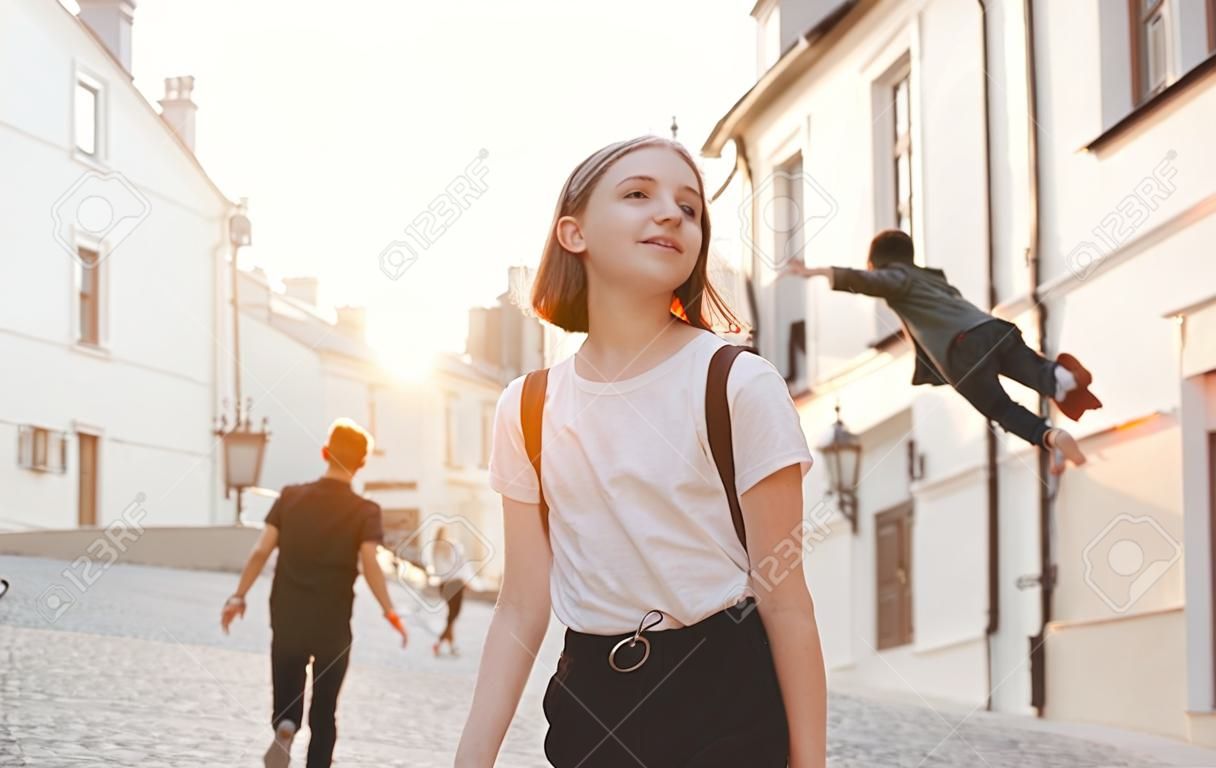 Aantrekkelijk meisje houdt een jonge man bij de hand en gaat met hem mee langs de straat van de oude stad op de achtergrond van de zonsondergang. Gelukkige man volgt een meisje op de achtergrond van de zonsondergang. Volg mij.