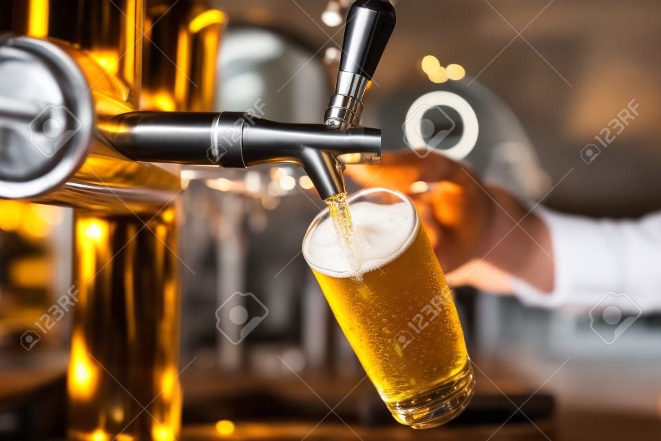 レストランやパブで提供ドラフト ラガー ビールを注ぐビールでバーテンダーの手をタップします。