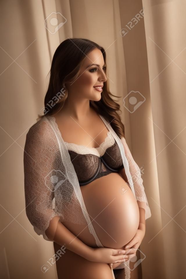 Foto van mooie zwangere vrouw dragen lingerie en poseren in de kamer