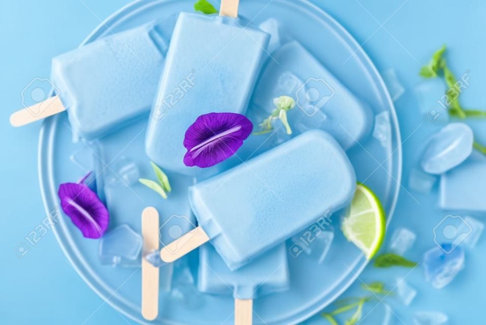 자연적으로 유기농 여름 과자, 나비 완두콩 꽃 차, 회색 콘크리트 배경 복사 공간으로 만든 파란색과 보라색 아이스크림 아이스 캔디